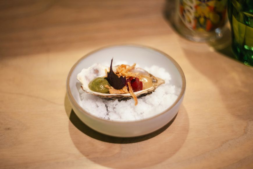 Plato de restaurante de alta cocina. Una ostra gourmet con coloridos ingredientes sobre hielo